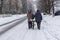 Elderly pair walking on a winter street rolling old bicycle loaded with bags in Dnepr city, Ukraine