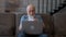 Elderly pensioner with gray beard communicates video chat with his native family, emotionally communicates with