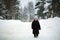 An elderly pensioner woman walking along the snowy winter street.