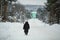 Elderly pensioner woman walking along the snowy winter street of the village.