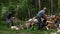 Elderly person and young man are chopping birch logs with an axes outdoors