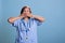 Elderly physician nurse in blue uniform covering mouth with hands