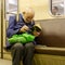 Elderly, poor, lonely man in broken glasses enthusiastically reading a tattered book