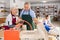 Elderly potter teaches woman how to roll clay on a craft machine clay press roller