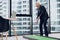 An elderly respectable man in a strict business suit posing in the office playing a mini golf game