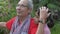 Elderly retire gray hair grandfather taking care of flowers in the garden while adorable granddaughter approach and embraces him.