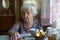 An elderly sad woman pensioner sitting at the table