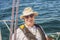 An elderly seafarer manages a sailing boat on a sunny summer day.