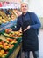 Elderly seller offering seasonal ripe fruits