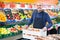 Elderly seller offering seasonal ripe fruits in local grocery