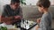 Elderly senior grandfather learning a 4 year old child playing chess, sitting at a table