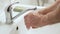 Elderly senior man washing his hands under tap water faucet, closeup detail - hygiene during coronavirus outbreak