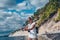 Elderly senior traveling backpacker mature woman tourist taking photos sea coast, rocks, blue sky