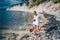 Elderly senior traveling backpacker mature woman tourist taking photos sea coast, rocks, blue sky