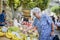 Elderly senior woman buying fresh vegetables and fruits in farmer`s market during summer day in provence france