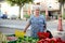 Elderly senior woman buying fresh vegetables and fruits in farmer`s market during summer day in provence france