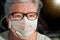 Elderly senior woman with glasses wearing hand made cotton mouth nose virus face mask. Coronavirus covid19 outbreak prevention