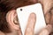 Elderly senior woman holding mobile phone next to her ear with hearing aid device, closeup detail