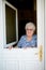 Elderly senior woman opening front door of house and welcoming people at home