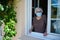 Elderly senior woman opening a window house and welcoming people at home wearing a surgical mask covid19