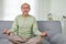 Elderly setting on sofa and doing yoga exercise