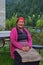 Elderly Sherpa woman who works in a local hostel in traditional attire sitting in the home garden