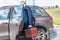 Elderly single man in a blue suit walks to his car with a supermarket trolley. Businessman and shopping.