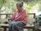 Elderly sits at balcony in garden with black and white cat.