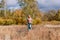 Elderly sixty-year-old woman in sportswear is engaged in Nordic walking with sticks in the forest in the autumn
