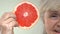 Elderly smiling woman showing grapefruit slice, anti-aging food, diet calories