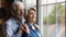 Elderly spouses hug look at window meet twilight years together