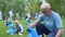 Elderly volunteer collecting plastic trash putting in garbage bag, eco event