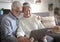 Elderly web surfer. Two smiling senior people sharing and looking at laptop and planning a new travel. White hair - couple in