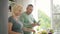 Elderly wife helping husband in salad cooking in kitchen.