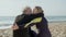 Elderly wife and husband hugging on shore after surf workout