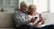 Elderly wife and husband rest on sofa with smartphones