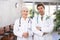 Elderly woman and adult man doctors posing in clinic reception