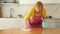 Elderly woman in apron wipes table with rag and disinfects kitchen surface