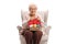 Elderly woman in an armchair knitting and smiling at the camera