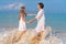 An elderly woman and beautiful girl on the beach. Grandmother granddaughter holding hands on the background of the waves of the
