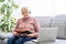 elderly Woman with bible and laptop in front of her connected to online church services durring the covid 19 outbreak