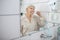 Elderly woman brushing her teeth in the bathroom