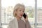 Elderly woman businessman talking on the phone in the office.  Concept: work for retirees, old workers, permanent leader