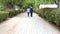 Elderly woman with caregiver walk towards a green alley