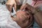 An elderly woman carries out a cosmetic procedure for the face.