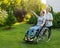 An elderly woman is carrying an adult daughter sitting in a wheelchair. Caucasian woman pointing her finger admiringly