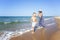 An elderly woman catches up with a boy on a sandy seashore on a sunny day. Active lifestyle, love, tenderness and travel