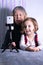 An elderly woman and a child are filming a video blog. Grandmother and granddaughter with a phone record video messages at home.