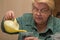 An elderly woman close-up pours the ground in a pot from a watering can.