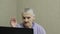 An elderly woman communicates on a laptop via video calling